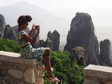 Woman In Blue And Yellow Floral Dress Taking Photo Of Mountain