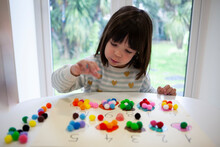 Young Girl Learning Numbers Using Cartoon Paper And Colorful Beads