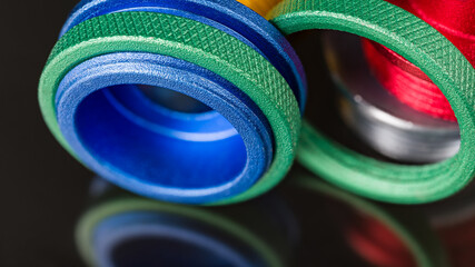 Green knurled nuts and colored router guide bushings detail on black background with beautiful reflection. Closeup of anodized aluminum copy rings. Threaded template for wood shaping or trimming tool.