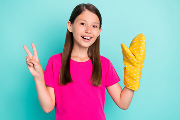 Poster - Portrait of attractive cheerful schoolkid chef showing v-sign wearing glove isolated over bright teal turquoise color background