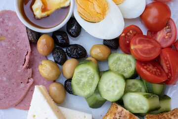 Poster - Breakfast of different vegetables, olives, cheese, and bacon with sauce on a white plate