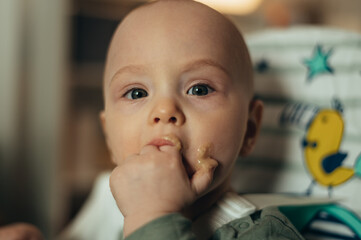 Baby eating with a face stained in food while in a child's dining chair