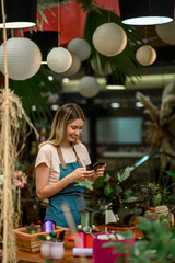 Wall Mural - Florist using smartphone in a flower shop