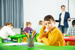 © JackF - Portrait of upset boy in schoolroom on background with pupils studying with teacher