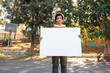 © Jacob Lund - Teenage boy holding a blank placard in a park