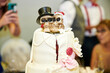 White wedding cake with a skull topper and red roses, the bride and groom in the form of a skeleton