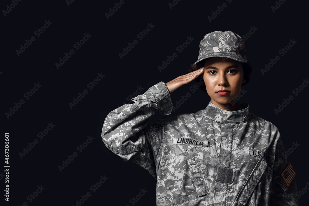 Saluting African-American female soldier on dark background