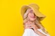 Portrait of attractive cheerful wavy-haired girl wearing straw sunhat touching shoulder isolated over bright yellow color background