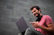 © Jelena - Handsome man working with laptop on city street. Man using his laptop while sitting on stairs outdoors