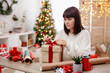 © Di Studio - Brunette woman wrapping the christmas gift in decorated room
