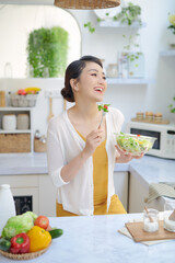 Wall Mural - woman eating healthy salad in modern kitchen