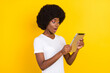© deagreez - Photo of cheerful nice amazed dark skin young woman look tablet isolated on yellow color background