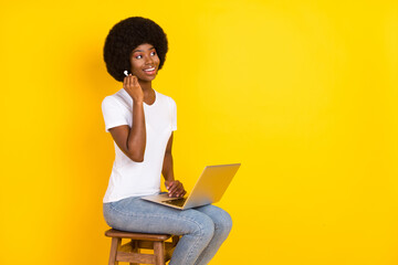 Poster - Photo of charming cute dark skin lady wear t-shirt sitting bar chair holding device looking empty space isolated yellow color background