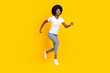 © deagreez - Full length photo of pretty sweet dark skin lady wear white t-shirt jumping high running fast smiling isolated yellow color background