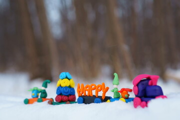 Wall Mural - Toy train with Christmas toys made of plasticine in the winter forest. Holiday decorations.