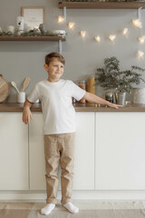 Minimalistic studio photo of eight old caucasian boy wearing in white t-shirt and beige pants for creating mockups for presentation graphic tees and pattern design