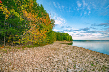 Wall Mural - autumn landscape, bright colorful leaves on the rocky riverbank.