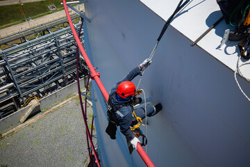 Wall Mural - Focus top view male worker down height tank roof rope access safety inspection of thickness storage tank gas