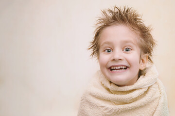 close-up portrait of joyful cute caucasian little boy looking at camera, toothy smiling, wrapped in 