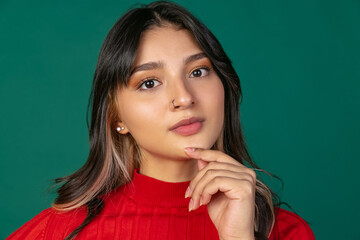 Wall Mural - Close-up portrait of young beuatiful girl, student in bright red sweater isolated on green studio backgroud.