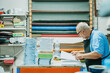 © ADDICTIVE STOCK - Attentive elderly male worker checking papers in printing studio