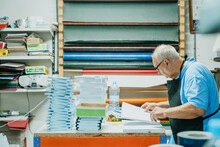 Attentive Elderly Male Worker Checking Papers In Printing Studio