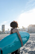 © ADDICTIVE STOCK - Curly haired woman with surfboard on sea shore