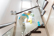 © ADDICTIVE STOCK - Smiling male cleaner wiping glass on staircase