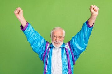 Poster - Photo of funny lucky mature guy dressed blue sport suit rising fists smiling isolated green color background