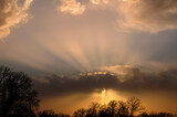 Fototapeta Na sufit - Dramatic storm clouds in the evening, with sun rays shining through the clouds near sunset