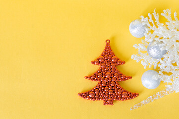 Christmas decorations, a red Christmas tree and silver balls with white branches on a yellow background with empty space