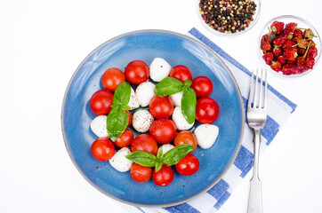 Wall Mural - Vegetable salad with mozzarella balls on plate, white background. Studio Photo.