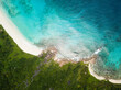 Beautiful tropical forest meets ocean with white coral beach, and rocks. Drone image from high above, birds eye view. 