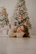 © ANNA - The theme of Christmas and New Year. Portrait of a girl lying under the Christmas tree in 2022.
