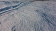 Snow on a frozen lake. Full screen. Close-up. A smooth surface, and in the upper left corner - snow dunes form a pattern. A patch of ice is visible in the distance. Baikal