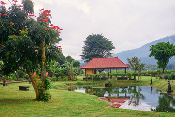 Canvas Print - Traditional balinese architecture.  Tiled pavilions near the lake in the green park.