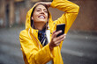 Close-up of a young girl with yellow raincoat enjoying the music and a walk through the city on the rain. Walk, rain, city