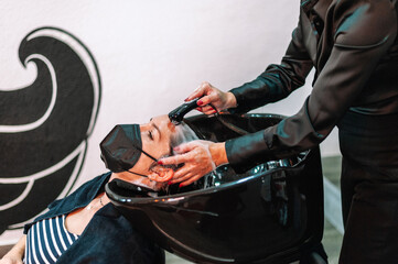 Wall Mural - Hair stylish washing hair to a client at the salon