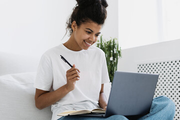 Young afro american woman watching online webinar on laptop