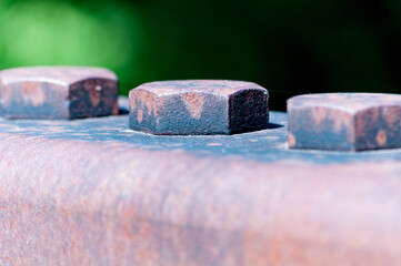 Poster - Closeup of three rusty bolts on the rusty surface in the blurred background