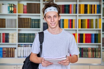 Wall Mural - Portrait of a male teenage student looking into the camera in the library.