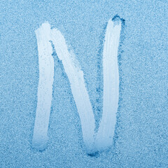 Wall Mural - The letter N written on glass with frost in the frost in winter, close up