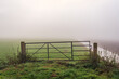 © Ruud Morijn - Skewed old iron gate between two concrete posts. The fence is located in front of a meadow in the Dutch province of North Brabant. It is a foggy morning in the autumn season.