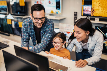 Happy family buying laptop in store.