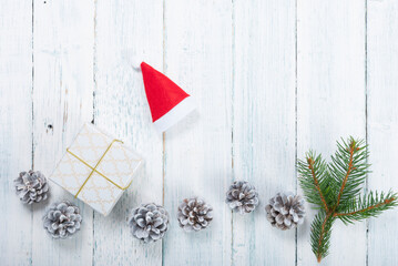 Wall Mural - pine branch, santa hat, gift box and pine cones on old white wooden