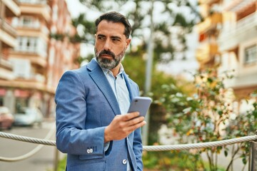 Wall Mural - Middle age businessman with serious expression using smartphone at the city.