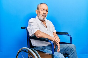 Wall Mural - Handsome senior man with beard sitting on wheelchair relaxed with serious expression on face. simple and natural looking at the camera.