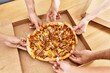 © Krakenimages.com - Hands of people taking portion of italian pizza on the table at home.