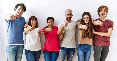 Wall Mural - Group of young friends standing together over isolated background pointing to you and the camera with fingers, smiling positive and cheerful