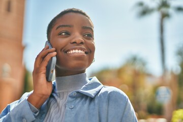 Wall Mural - Young african american woman smiling happy talking on the smartphone at the city